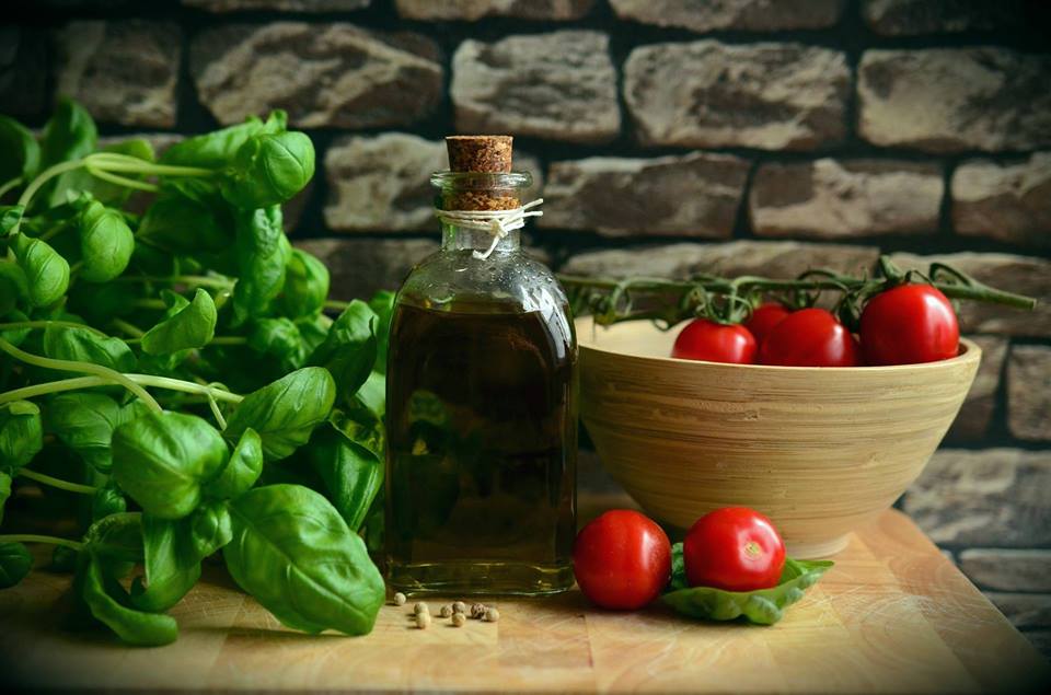 Kompozycja: pomidorki w misce, butelka oliwy, bazylia