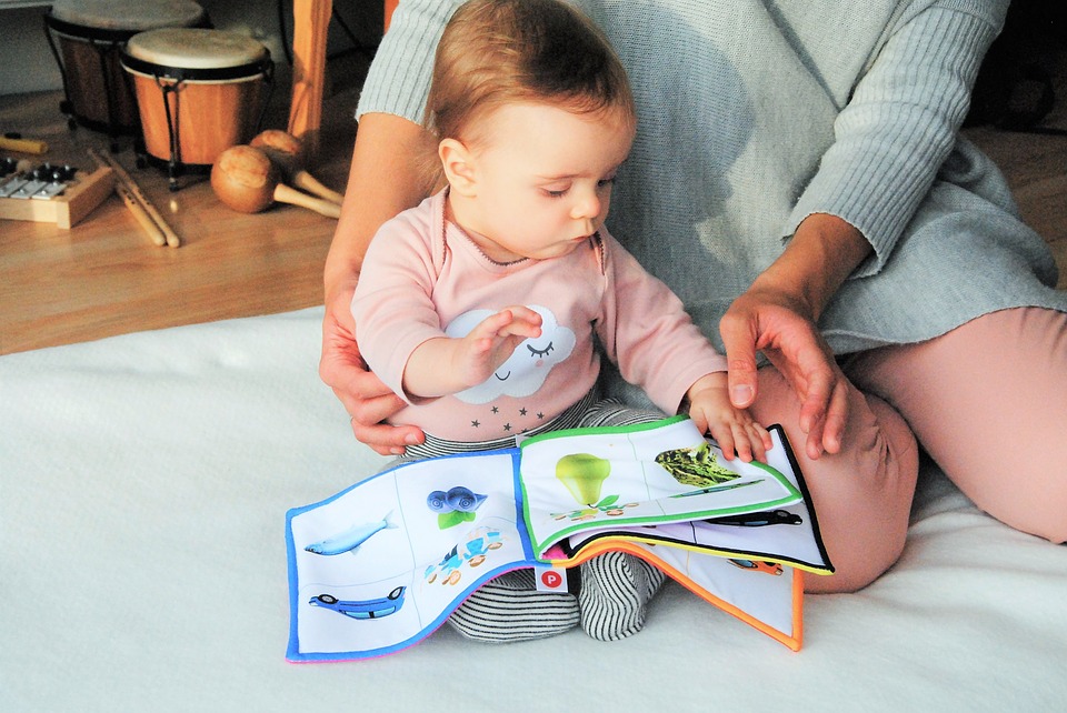 Bobas na kocyku oglądający z mamą książeczkę
