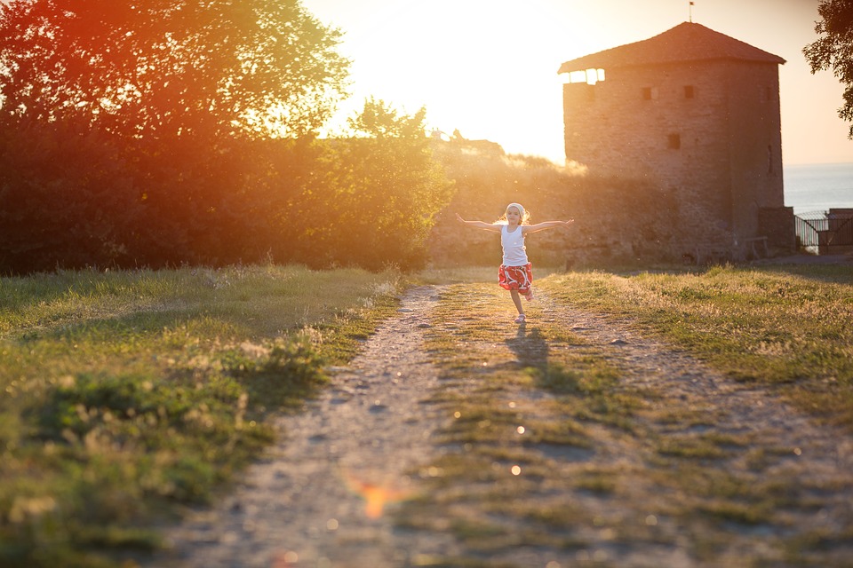 Dziecko biegnie po drodze przy zachodzie słońca