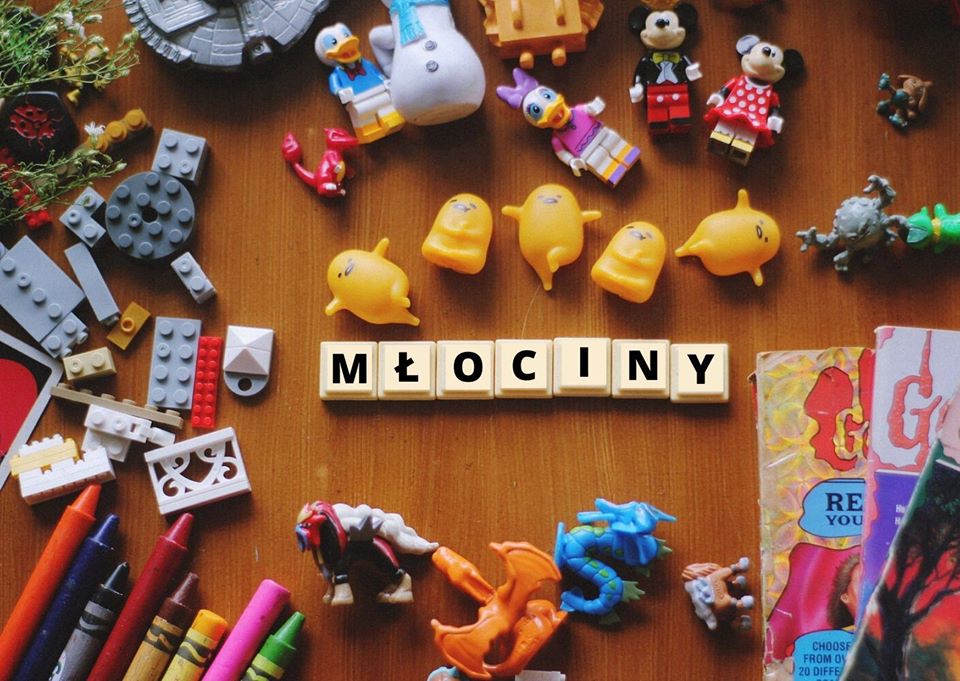 Napis Młociny z tabliczek scrabble pośród figurek i zabawek.