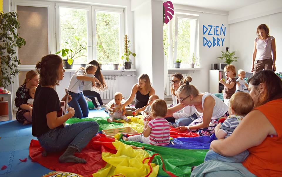 Grupa kobiet i dzieci na zajęciach "Brykanki-muzyczne poranki dla dzieci" w MAL Samogłoska.