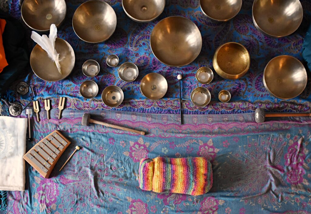Miedziane misy i gongi rozłożone na niebiesko-różowym dywanie w orientalne wzory.