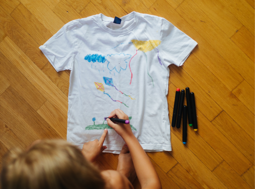Dziecko rysujące latawce na białej bawełnianej koszulce
