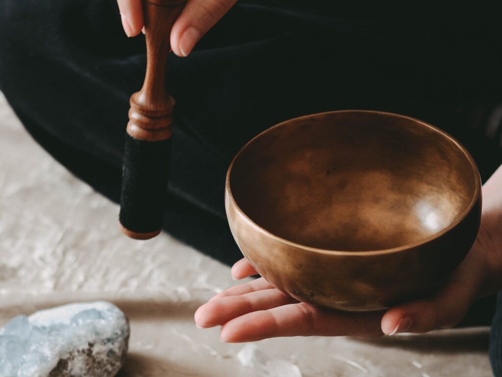 Dłoń trzymająca miedzianą misę, kamienie, kamienna misa z ziołowym pęczkiem.