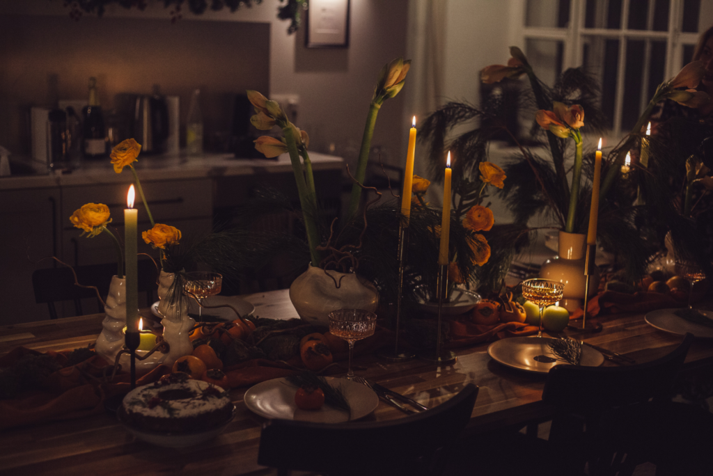 Zastawiony stół ze świecami, w przyciemnionym pomieszczeniu.