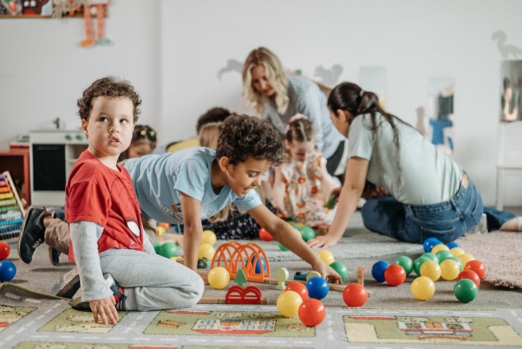 Dzieci bawiące się kolorowymi zabawkami na dywanie.