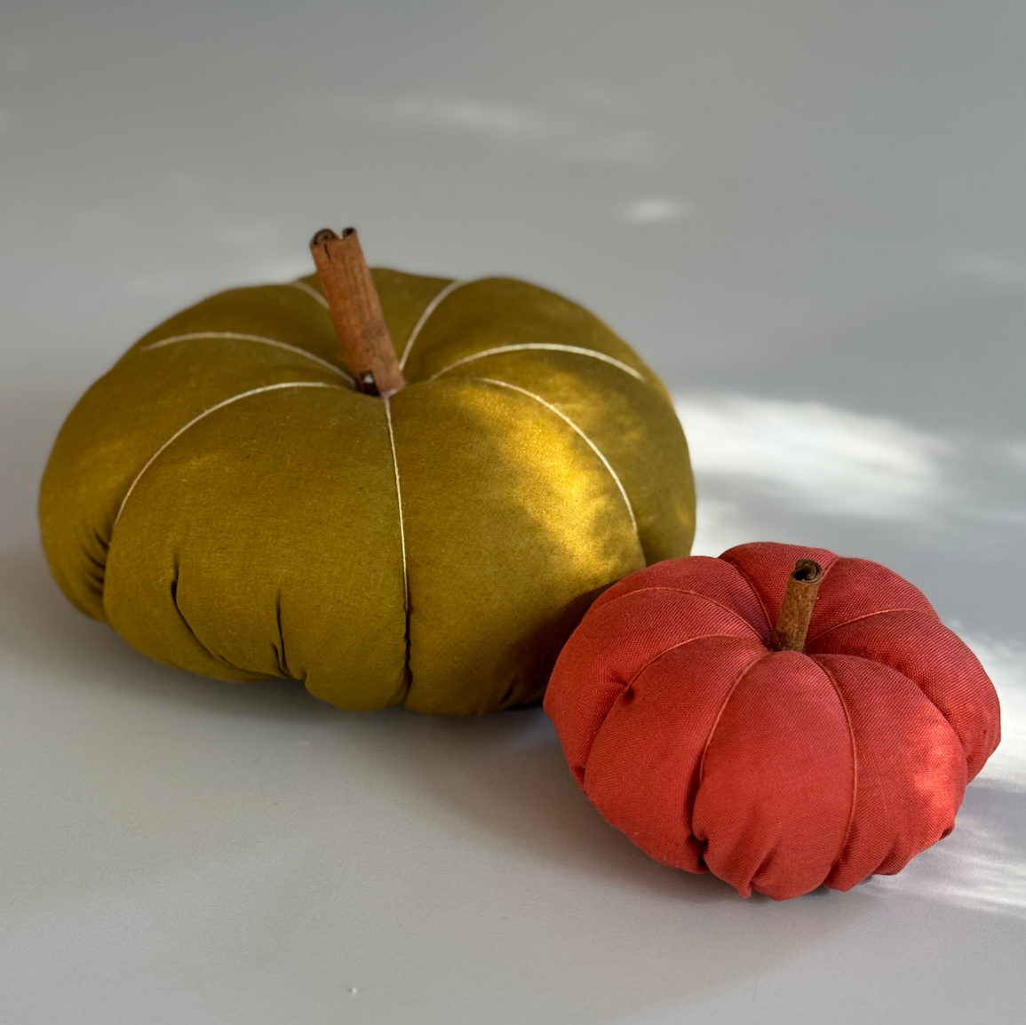 Dwie dynie wykonane z materiałów w kolorze żółtym i pomarańczowym.