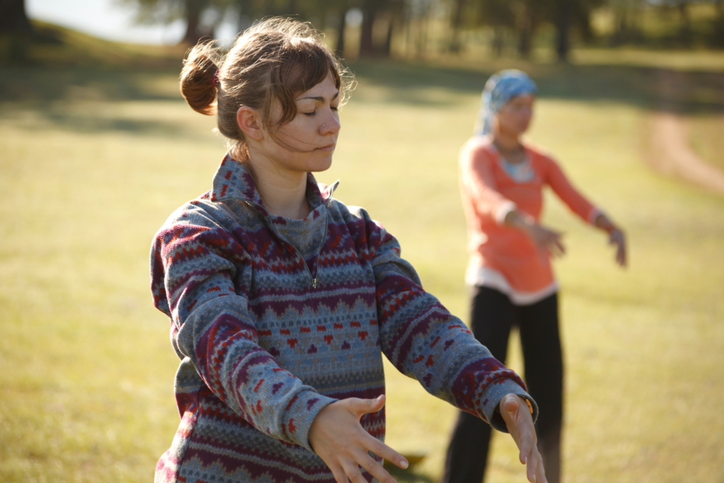 Dwie kobiety ćwiczące qigong w plenerze.