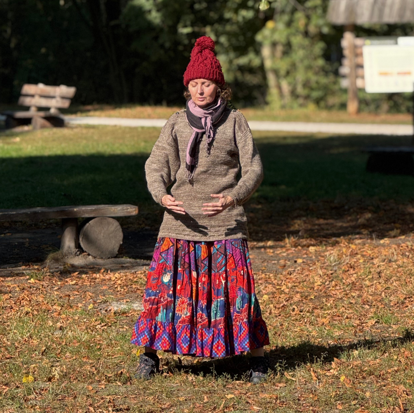 Osoba w pozycji qigong ćwiczy w plenerze.