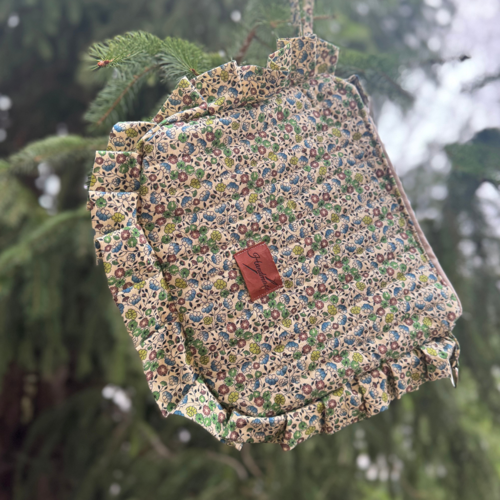 Kolorowa kosmetyczka z falbanką na tle drzewa.