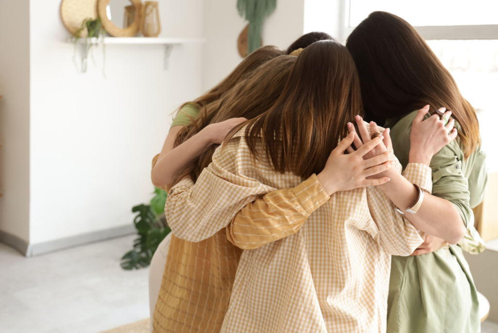 Grupa kobiet obejmuje się w kręgu.