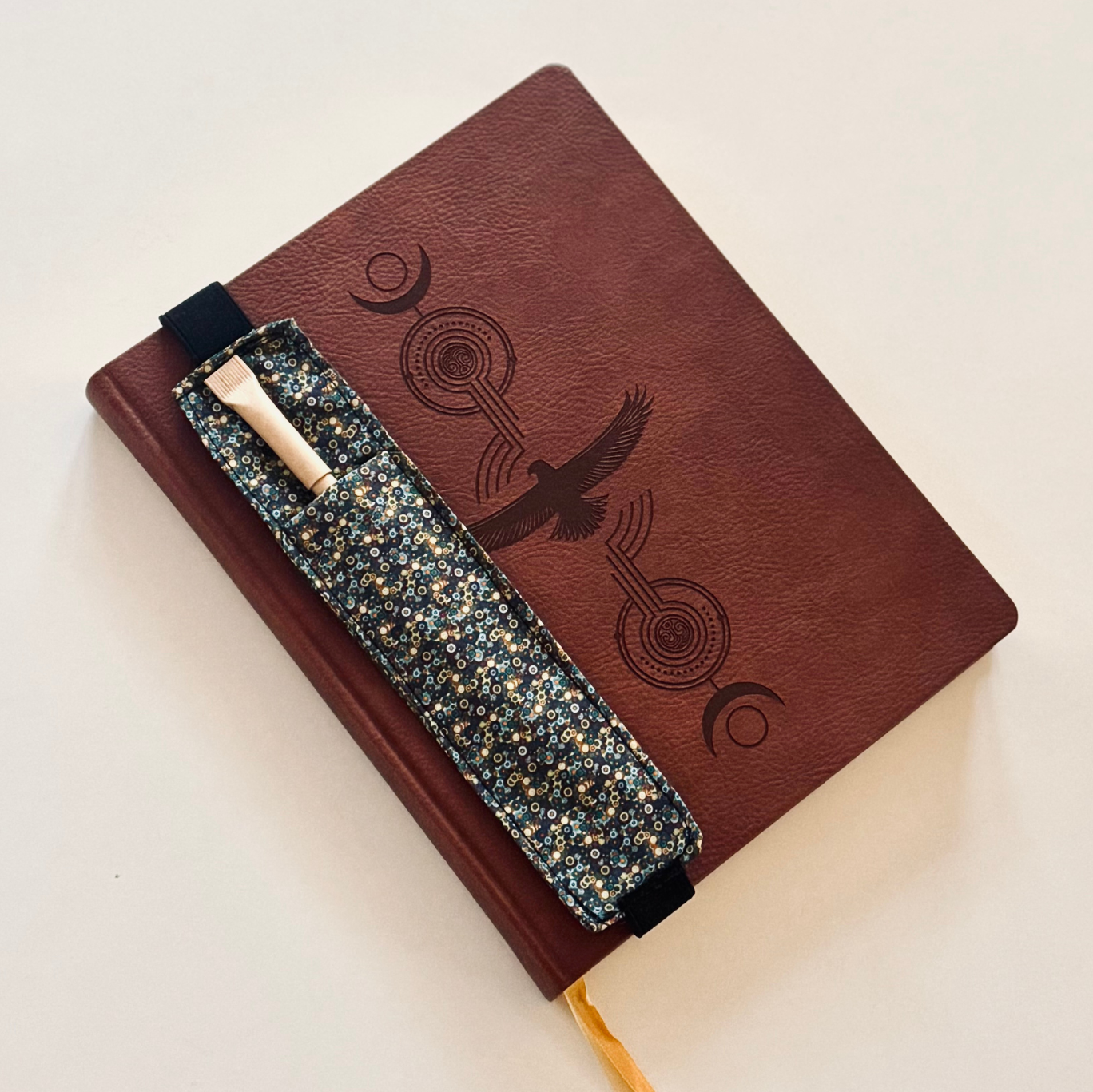 Skórzany notes z materiałową zakładką z kieszonką na długopis.